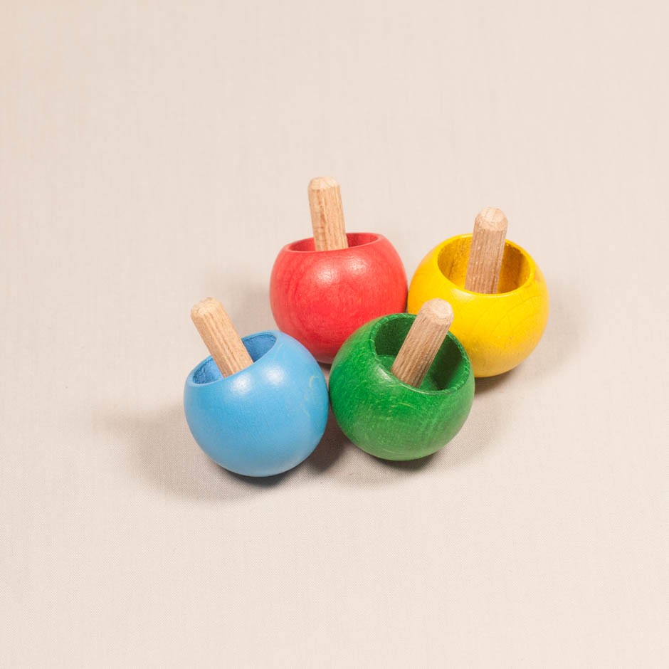 Vista superior de cuatro peonzas bola de madera en diferentes colores.