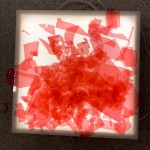 Detalle de recortes de papel de celofán rojo sobre un proyector de luz. 