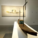 Sala de exposición. Al fondo, la obra «Barca blanca y dorada», sobre tela en arpillera y cobre. En primer plano, En primer plano, la escultura 'Barca con cofre' en madera, bronca y pan de oro.