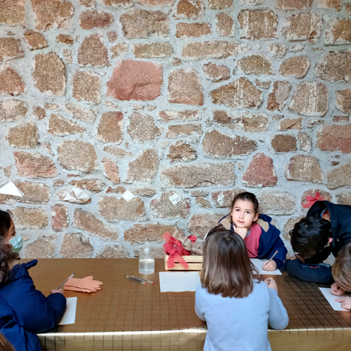 Alrededor de una mesa, un grupo de 6 peques creando sus figuras en papiroflexia.