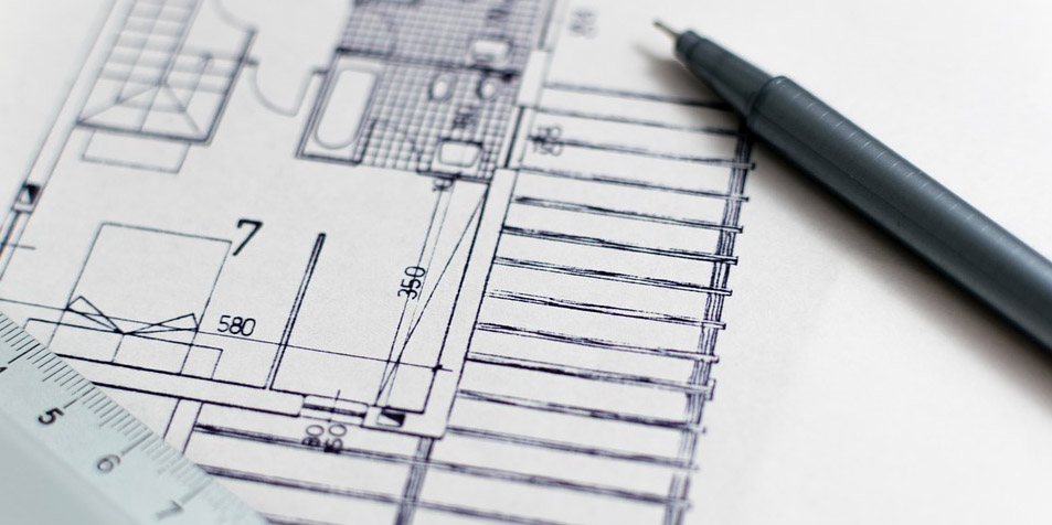 Sobre un plano arquitectónico de una construcción, una regla graduada y un lápiz.