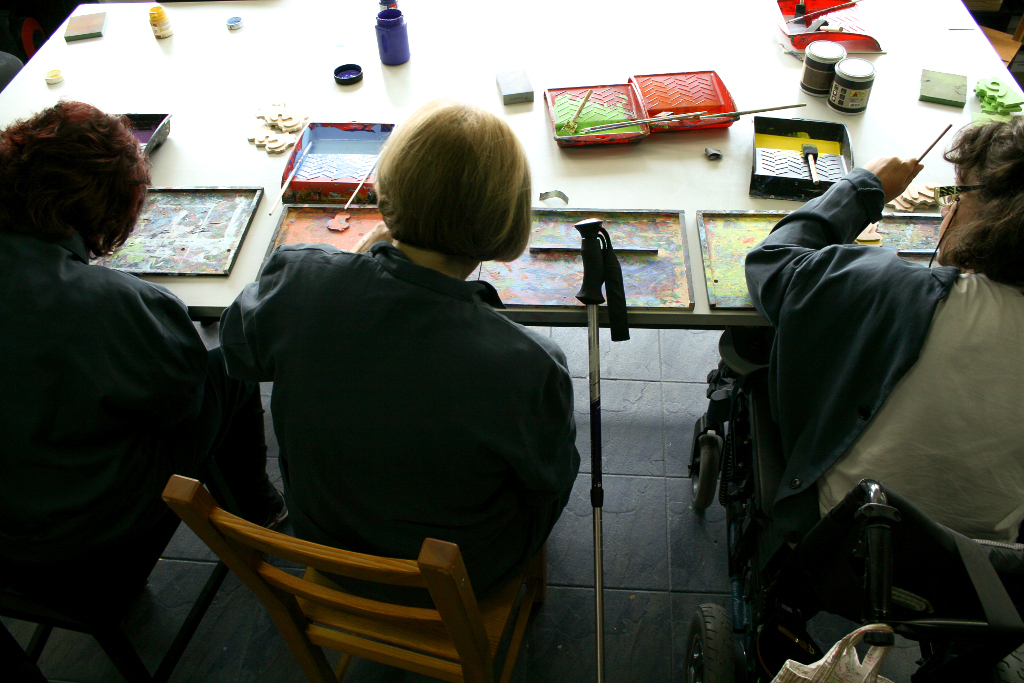 Vista posterior de tres mujeres pintando manualmente las piezas de los puzzles Manualia.