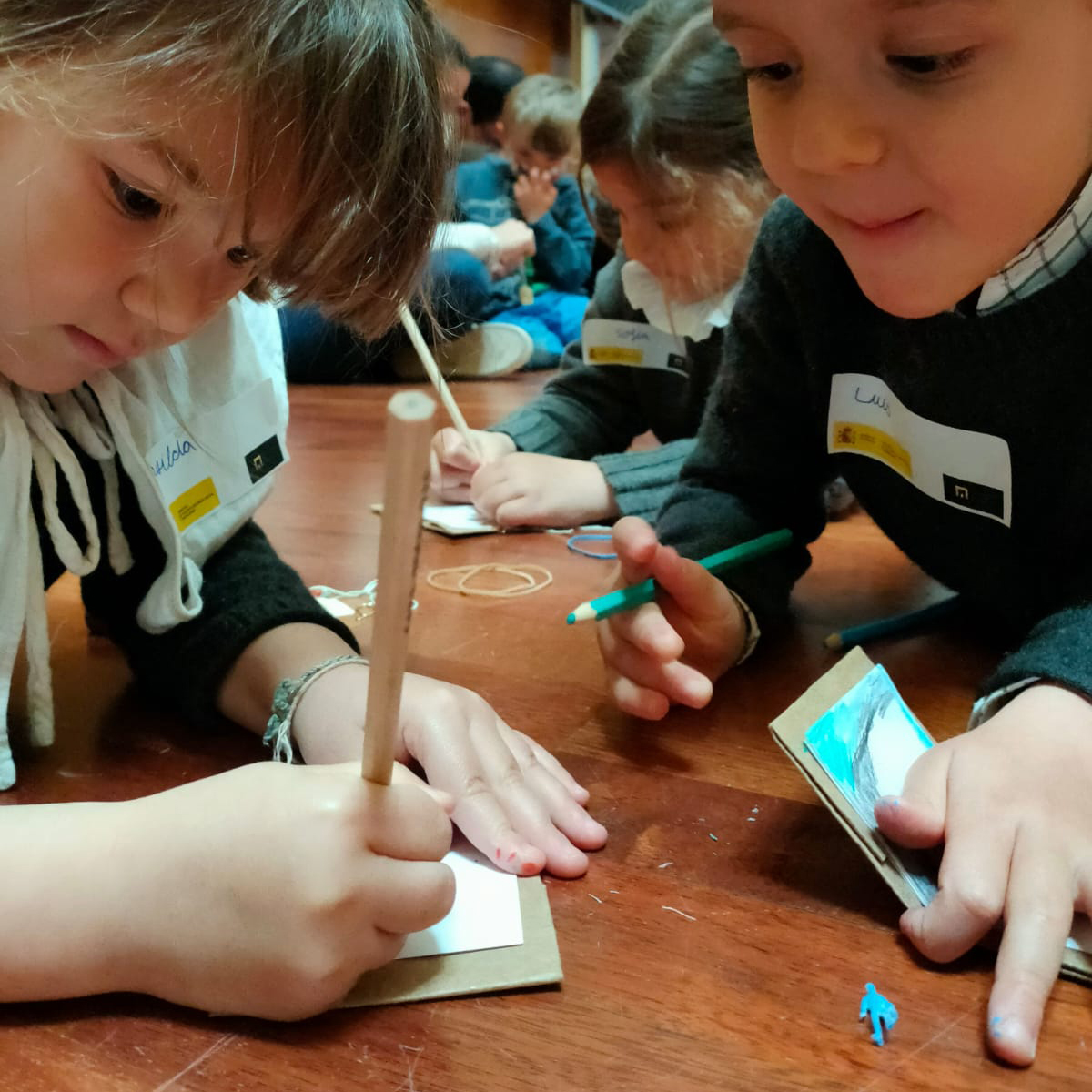 Plano detalle de varios niños en el sueño escribiendo y dibujando sobre sus carpetas de cartón. 