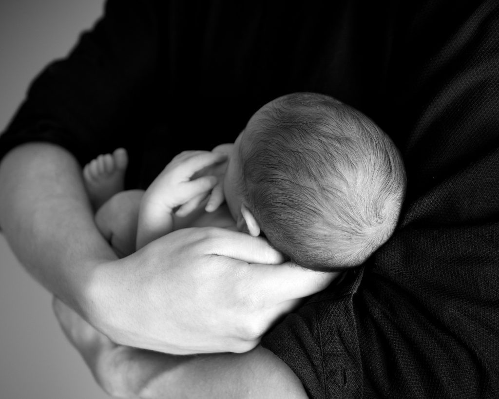 Detalle de una madre sosteniendo en brazos una bebé.