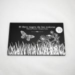Libro “El libro negro de los colores”. En portada, la ilustración de una mariposa volando sobre hierba y flores.