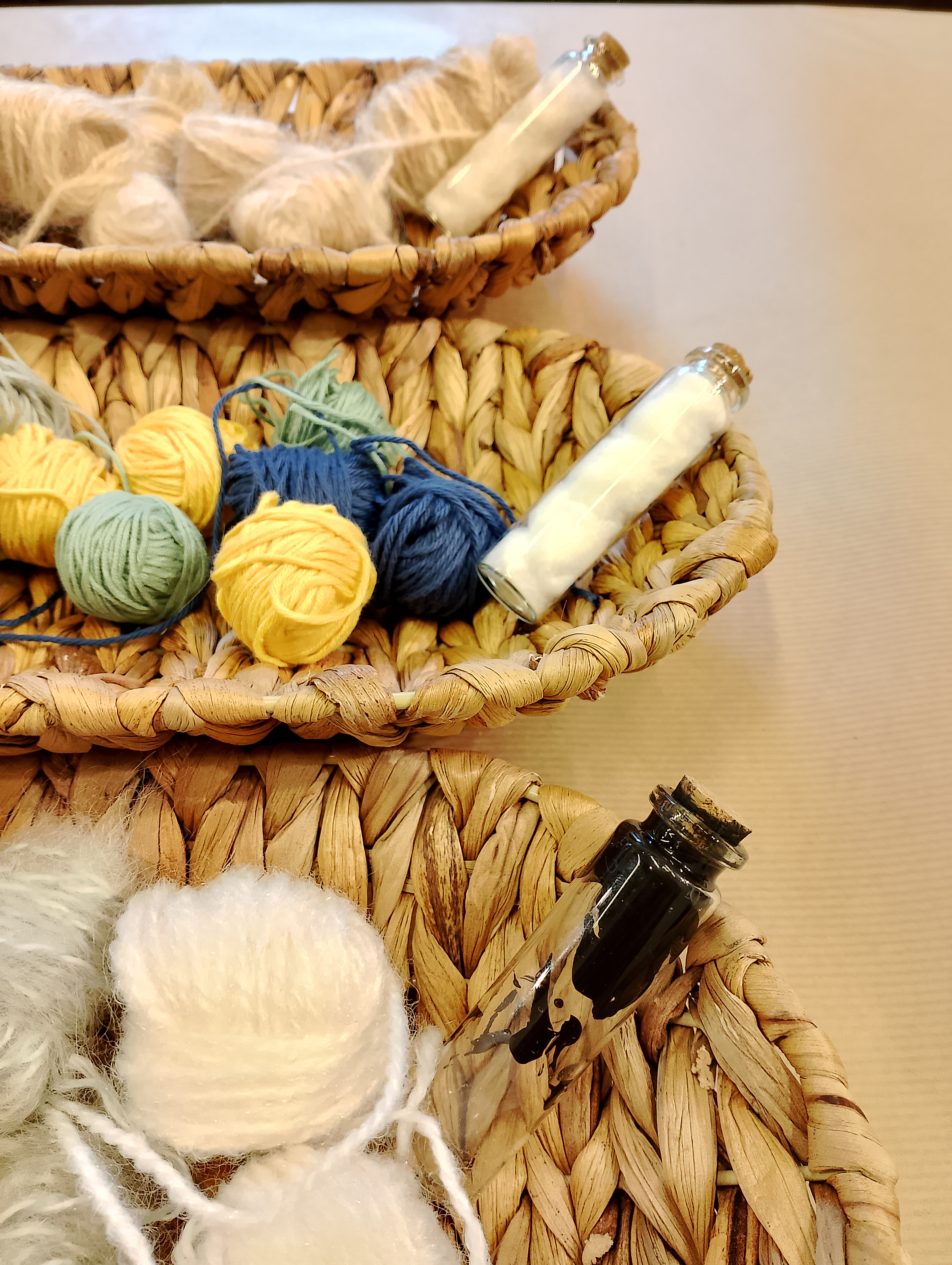 3 Cestas con distintos ovillos textiles. en cada cesta hay una probeta que contiene el textil puro